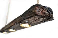 a wooden light fixture with two lights on the top and one in the middle hanging from a rope