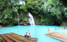 people are standing on rafts in the water near a waterfall