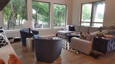 a living room filled with lots of furniture and large windows above the couches in front of them