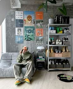 a man sitting on a couch in front of a book shelf filled with books and shoes