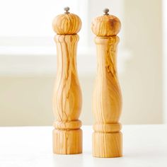 two wooden candlesticks sitting on top of a white table next to each other