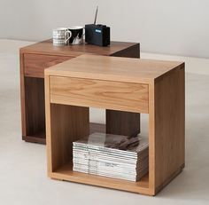 a wooden table topped with magazines and a radio on top of each other next to a cup