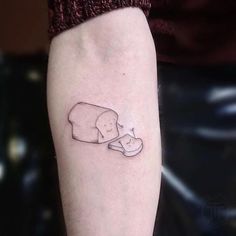 a person with a small tattoo on their arm holding a piece of bread in the shape of a heart