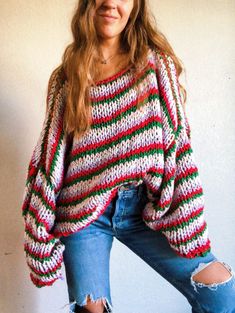 a woman wearing ripped jeans and a colorful striped sweater is posing for the camera with her hands in her pockets