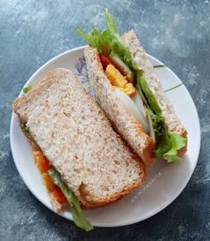 a white plate topped with a cut in half sandwich