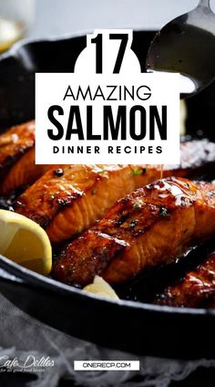 salmon being cooked in a skillet with lemon wedges