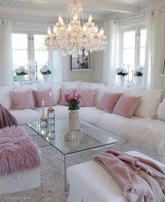 a living room filled with lots of white furniture and pink pillows on top of it