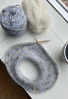 yarn and knitting needles sitting on top of a table next to a ball of yarn