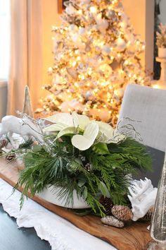 a christmas centerpiece with white flowers and greenery