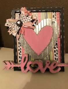 a pink and black card with the word love on it's side, sitting on top of a table