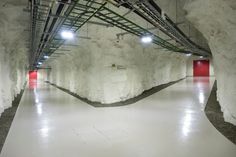 an empty white room with red doors and pipes on the ceiling, in front of snow covered walls