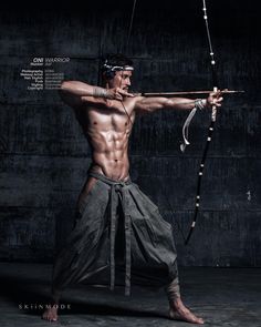 a man with no shirt holding a bow and arrow