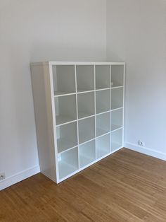 an empty room with white shelving unit in the corner and hard wood flooring