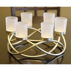 a set of six candles sitting on top of a metal candle holder with white glass votives