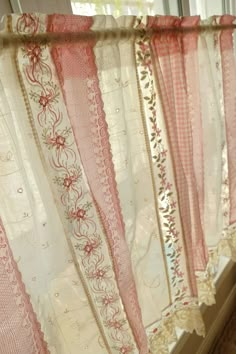 pink and white lace curtains hanging in front of a window