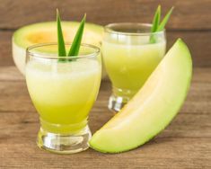 two glasses filled with green liquid next to an avocado