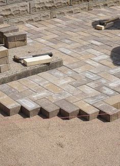 a brick patio with several pieces of wood on the ground and one piece of concrete in the middle