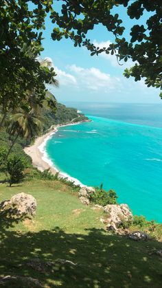 the ocean is blue and green with white sand on it's shore, surrounded by trees