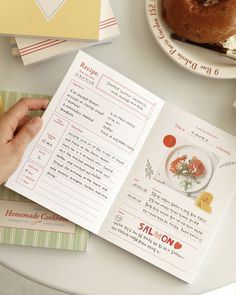 a person is reading a recipe book on a table with other food and drink items