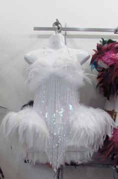 a white teddy bear sitting on top of a toilet covered in sequins and feathers