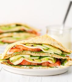 a white plate topped with a cut in half sandwich next to a glass of milk