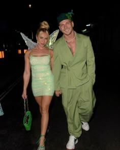 a man and woman dressed as tinkerbells walking down the street at night