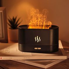 a black speaker with flames on top of it sitting on a table next to a potted plant