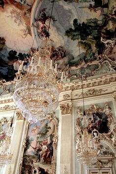 a chandelier hanging from the ceiling in a room with paintings on the walls