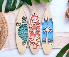 three wooden surfboards sitting on top of a table next to plants and potted plants