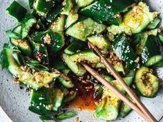 a white plate topped with cucumbers and chopsticks