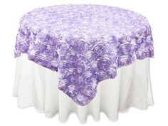 a round table covered in purple roses on a white surface with a blue and white cloth