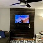 a flat screen tv mounted to the side of a wall in a living room next to a couch