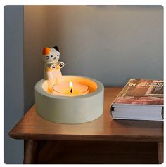 a cat figurine sitting on top of a table next to a book and candle