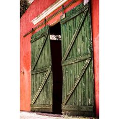 an open door to a red building with green shutters on the outside and inside