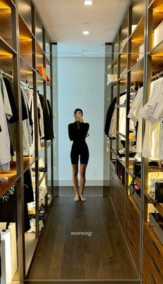 a woman standing in front of a closet filled with clothes and other clothing on shelves