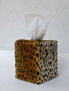 a tissue dispenser made out of an animal print material with white tissue paper in it