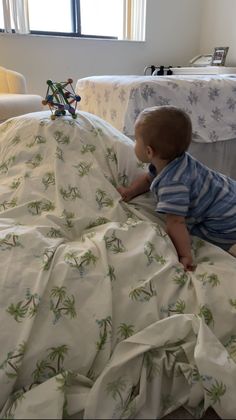 a baby sitting on top of a bed under a blanket