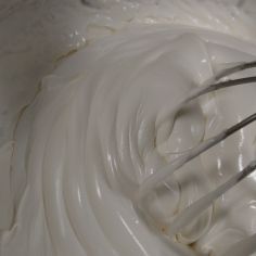 a whisk in a mixing bowl filled with white cream