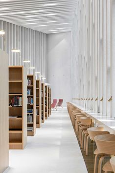 an empty library with rows of bookshelves and tables in the foreground, along with chairs on either side