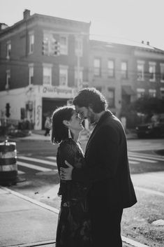 a man and woman standing next to each other in front of a building on the street