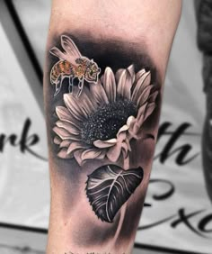 a sunflower and a bee tattoo on the leg