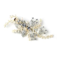 a white brooch with pearls and crystal stones on the front, sitting on a white surface