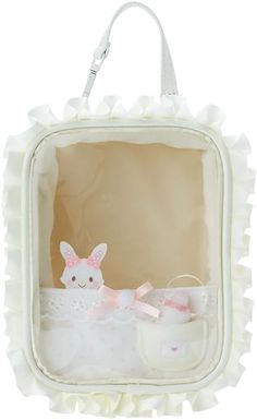 a small white bag with a stuffed animal in it's pocket and some bows on the handle