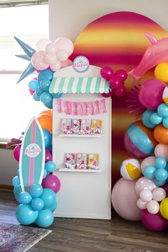 there is a refrigerator decorated with balloons and other items in the room that includes a surfboard