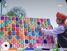 a man standing next to a giant display of colored spools