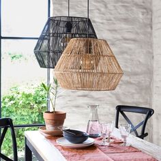 a dining room table with plates and glasses on it, next to a hanging light fixture