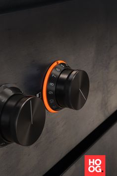 an orange knob is on the side of a black cabinet with two round knobs