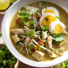 a white bowl filled with soup and topped with an egg, meat, and veggies