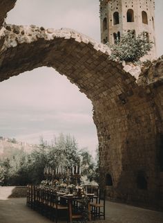 an outdoor dining area with table and chairs under an archway that leads to a castle like structure