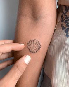 a woman with a shell tattoo on her arm